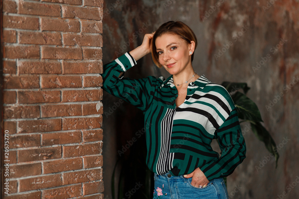 Beautiful young woman in grenn jacket posing over brick wall. Casual home lifestyle photo