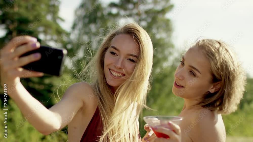 Attractive blonde girls posing and playing with their hair for selfi in swimsuit and bikini a background of nature Attractive blonde girls posing and playing with their hair for selfi in swimsuit and bikini a background of nature