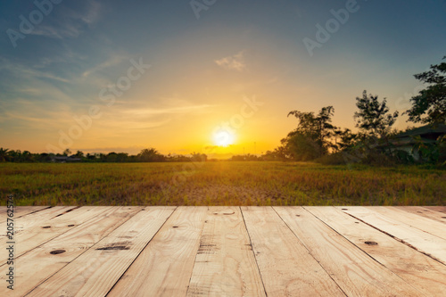 Empty wooden table top and display montage with blur background field sunset.