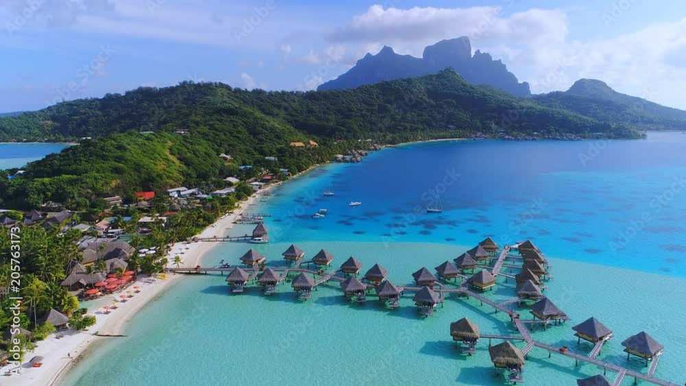 Aerial view of tropical paradise of Bora Bora island, turquoise crystal clear water of scenic blue lagoon, typical over water bungalows, Matira Point - South Pacific Ocean, French Polynesia from above