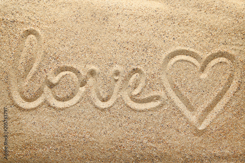 Inscription Love and heart drawn on beach sand