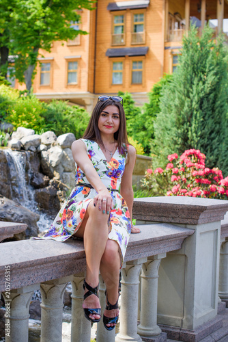 Hispanic pretty young woman rest at summer time. Latina Woman wear flowers print dress relax at nature and enjoy the life 