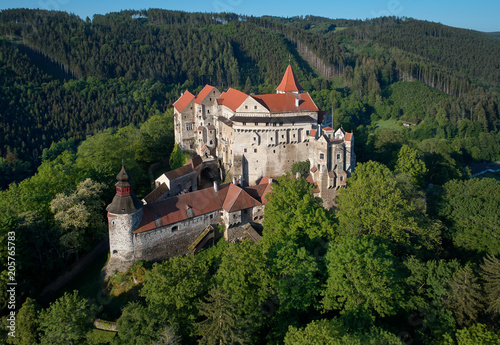 Moravian castle Pernstejn, standing on a hill above deep forests of the Bohemian-Moravian Highlands against blue sky. Aerial photography. Ancient royal castle in Czech landscape, czech travel place.