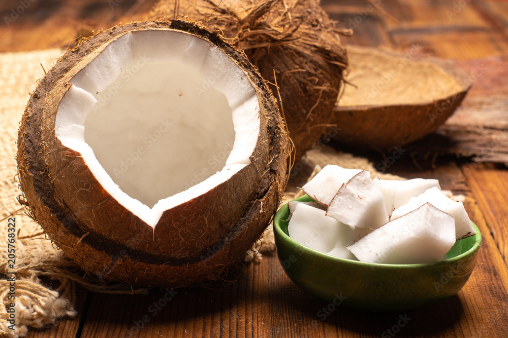 Big tropical palm nut coconut and coconut pieces ready to eat on wooden background close up Big tropical palm nut coconut and coconut pieces ready to eat on wooden background close up