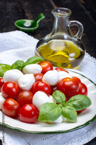 Italian soft cheese, young small balls mozzeralla cheese salad served with fresh basil, tasty ripe cherry tomatoes and Italian olive oil