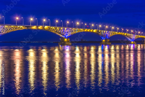 an automobile bridge across the Volga River at night, illuminated by the light of lanterns, the light of which is reflected in the river © Nemo67