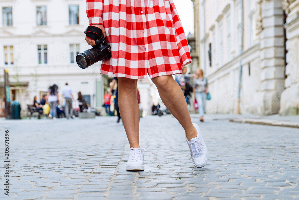 woman walking by city with camera in her hand