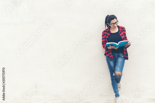 Asian woman standing and holding a book on wall white background. Education Concept.