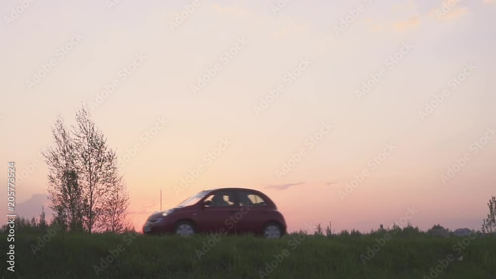 Silhouette of a car in a field at sunset. The road and the field. The car on the field. Silhouette of a car in a field at sunset. The road and the field. The car on the field.