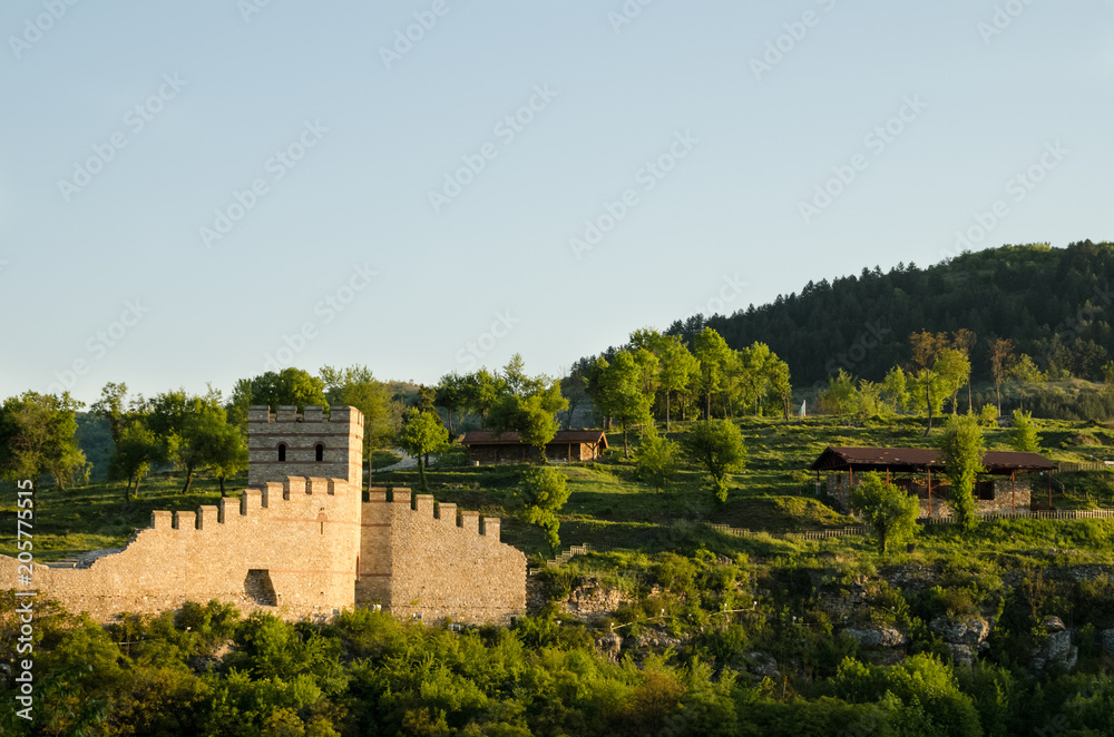 View of medieval Trapezitsa fortress and residential area of the city of Veliko Tarnovo in Bulgaria. Beautiful photo taken at spring morning when sun light just kisses ancient stone wall of the castle
