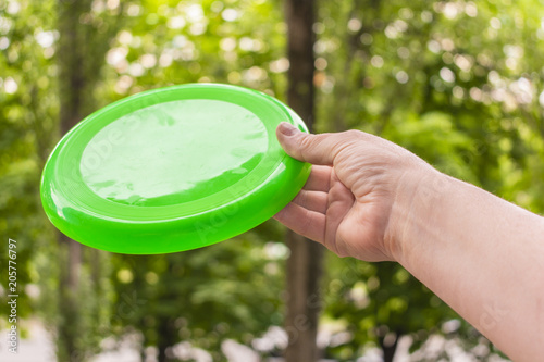 hand throwing a frisbee disc in the park on a summer day