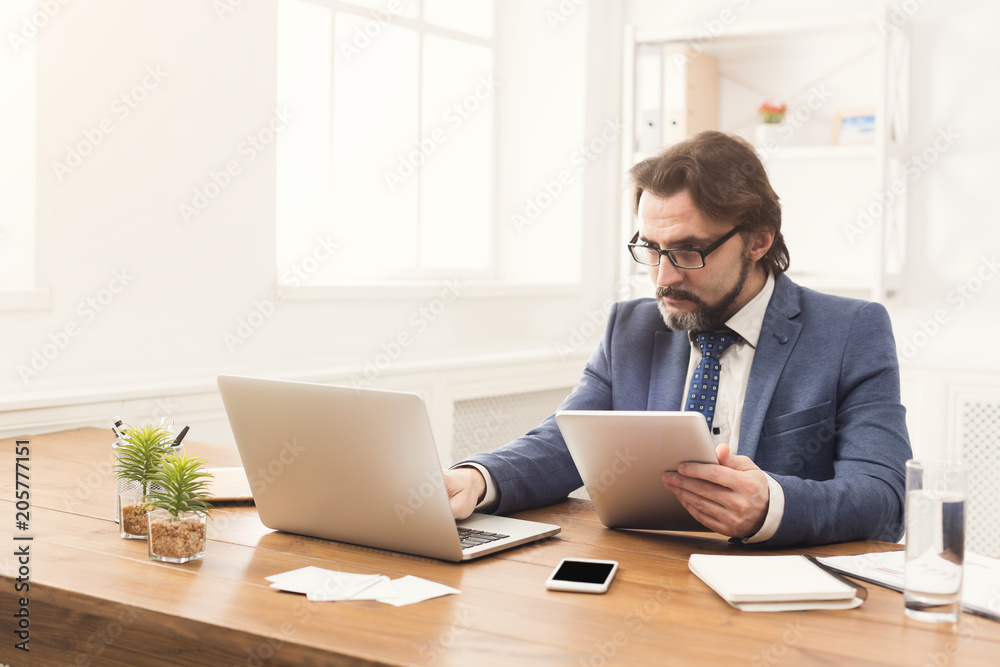Young smiling man using laptop in modern office