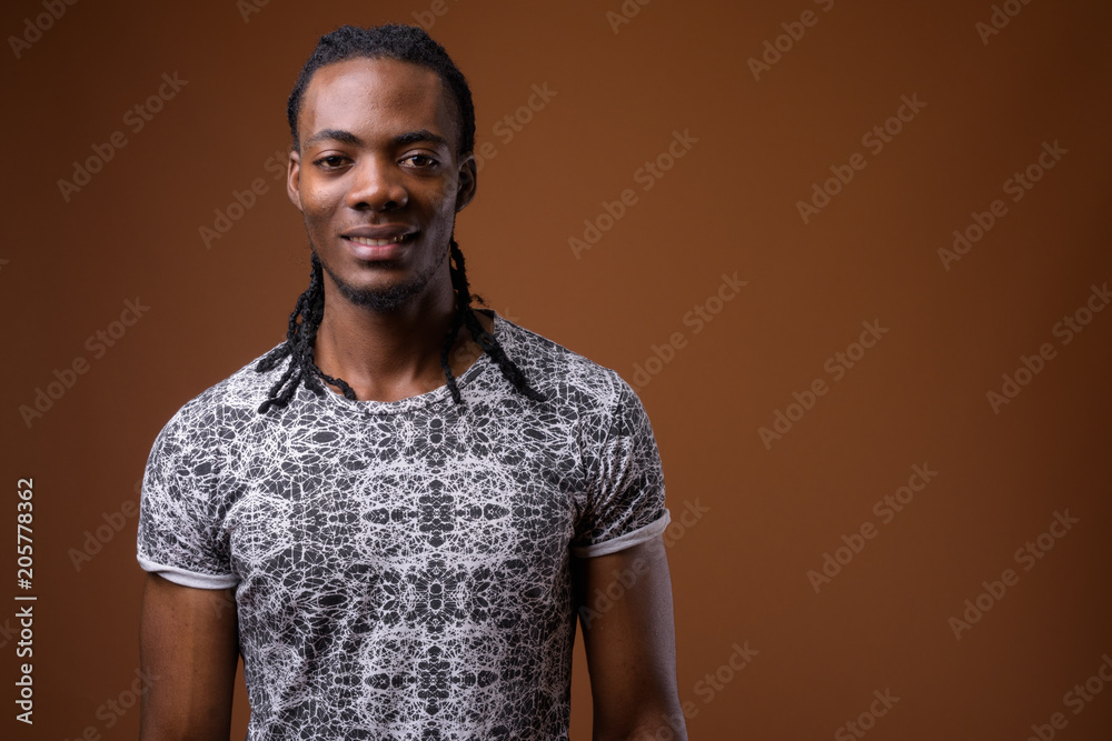 Obraz premium Young handsome African man against brown background
