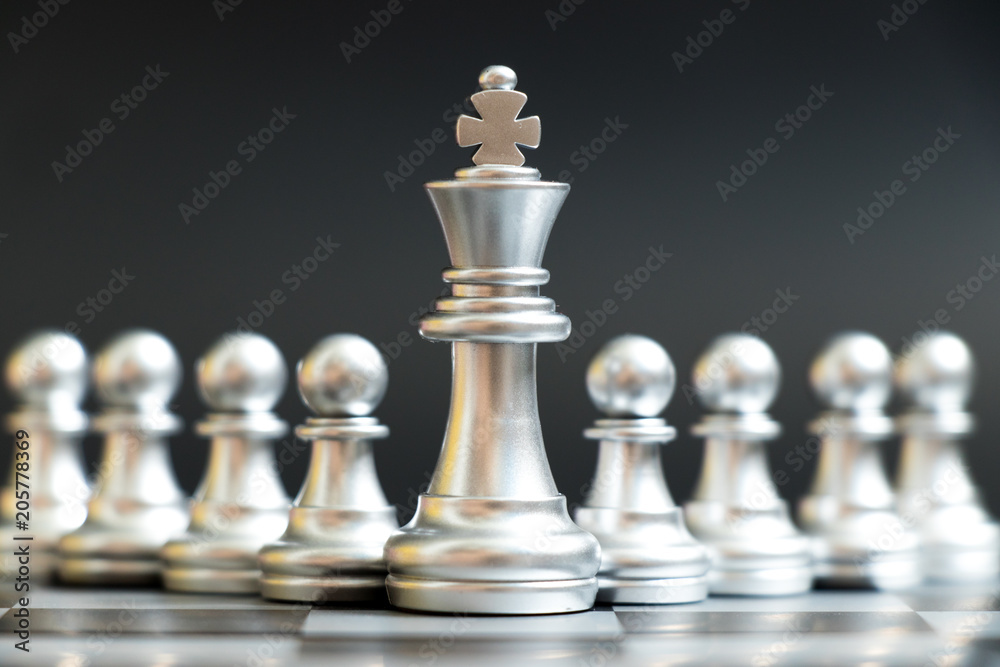 Silver king chess piece stand in front of pawn on black background (Concept of leadership, management) Silver king chess piece stand in front of pawn on black background (Concept of leadership, management)