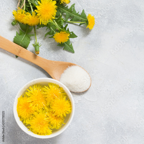 Fototapeta Naklejka Na Ścianę i Meble -  Ingredients for jam from dandelions. Fresh flowers of dandelions, sugar and water on a light summer background.