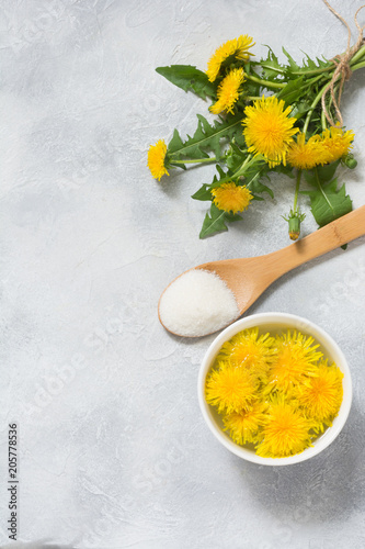 Fototapeta Naklejka Na Ścianę i Meble -  Ingredients for jam from dandelions. Fresh flowers of dandelions, sugar and water on a light summer background.