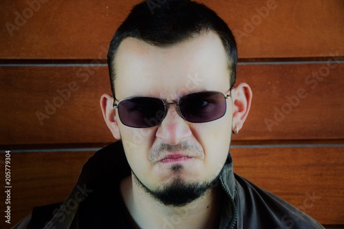 A man with a beard and sunglasses is looking angry at the camera