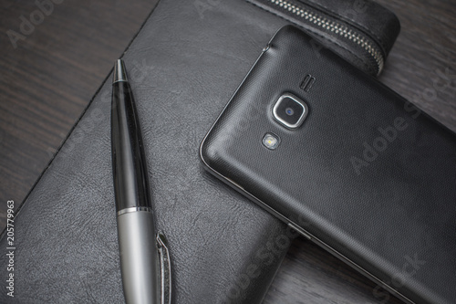 phone with a pen and purse on a wooden background