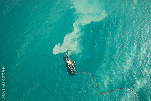 Ship dredging in turqouoise water. photo