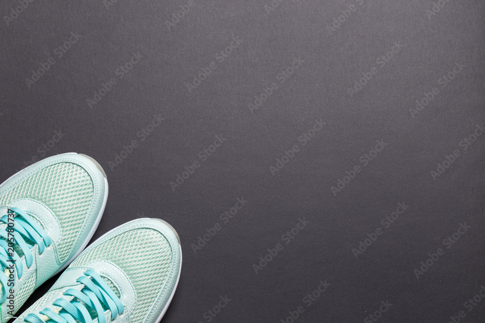 Turquoise sneakers and turquoise dumbbells with a white sole on a black background