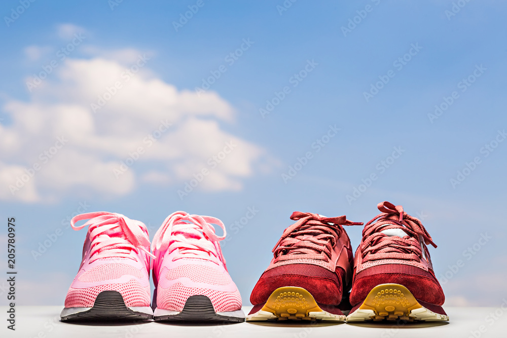 Two pairs of sneakers next to each other. Women's and men's. Against the background of the sky. Relations, friendship, joint leisure concept. Two pairs of sneakers next to each other. Women's and men's. Against the background of the sky. Relations, friendship, joint leisure concept.