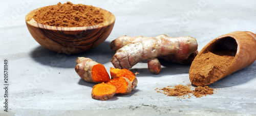 Turmeric powder and fresh turmeric on grey background