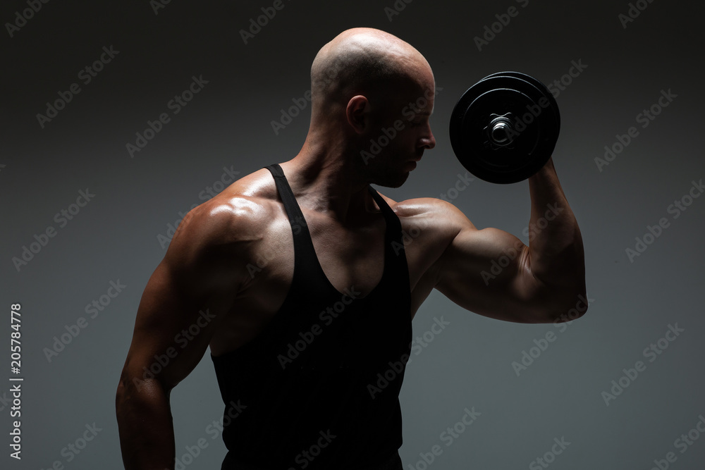 Strong young man bodybuilder performing exercise for biceps with heavy weights. Concept Gym Life Style.Toned Image.