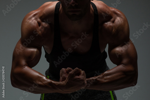 The torso of attractive male body builder flexing his muscles in studio shot. Concept Gym Life Style.
