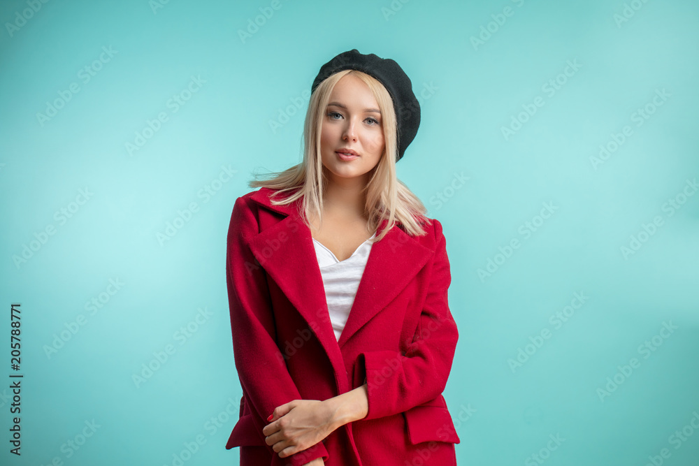 closeup photo of beautiful model in black beret and red overcoat isolated on the blue background. beauty concept closeup photo of beautiful model in black beret and red overcoat isolated on the blue background. beauty concept