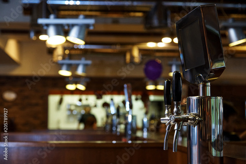 The system of bottling beer on the table of customers on a blurred background of the bar in the brewery. © Viktoriia