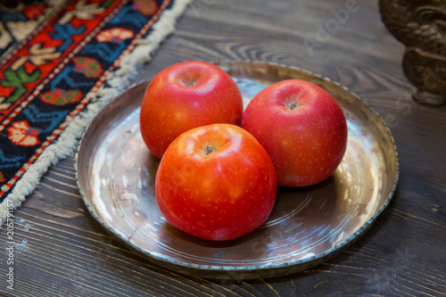 Three red apples are in a copper container