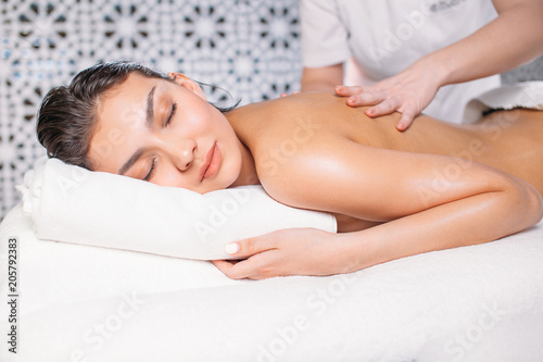 young woman is enjoying having relaxing massage in the massage salon. body massage. reabilitation program photo