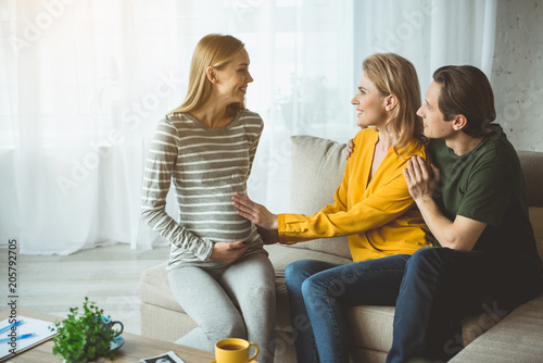 Thank you. Glad childless family is expressing their happiness while talking to surrogate expectant mother. Woman is touching female belly with love  photo