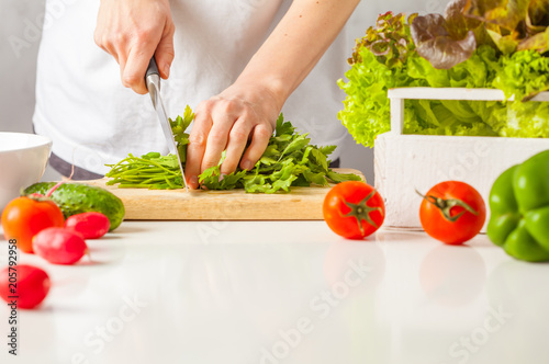 Woman cooking healthy food, cut green vegetable salad. Healthy lifestyle concept.