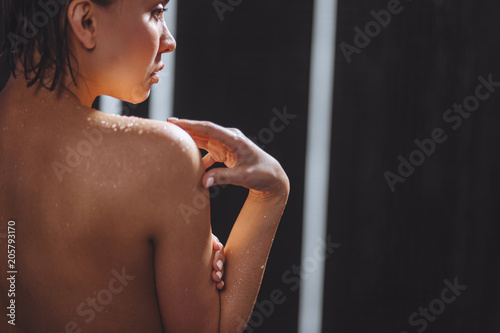 close up side back view phpto of naked Asian woman after getting out of the rain. rain drops on body photo