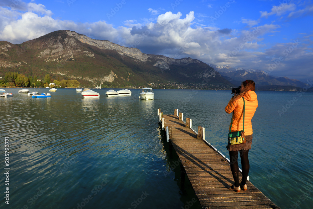 Young girl photographer taking photos on the shore of Annecy Lake, Haute Savoie, France, Europe