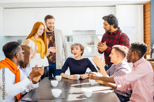 employees enjoying spending time togeter while drinking coffee in office kitchen photo