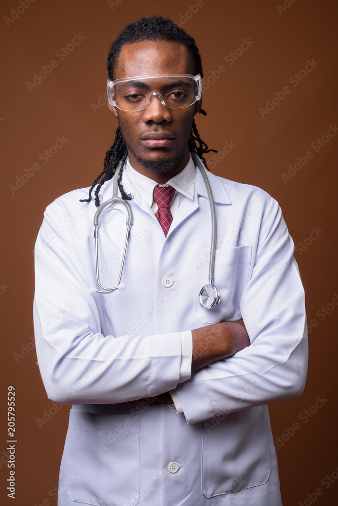 Young handsome African man doctor wearing protective glasses aga Young handsome African man doctor wearing protective glasses aga