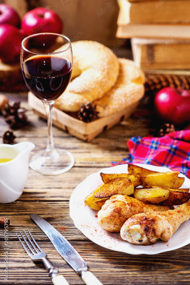a tasty dish for the holiday, a new year or Christmas, baked potatoes with chicken legs, spices, paprika, sesame, bagel, olive oil, red wine on a wooden background a tasty dish for the holiday, a new year or Christmas, baked potatoes with chicken legs, spices, paprika, sesame, bagel, olive oil, red wine on a wooden background