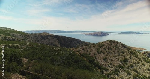 wide aerial shot of the croatian rocky coastline with the typical pine flora. in the background are many islands to see. camera moves forwards, close to the top of the trees