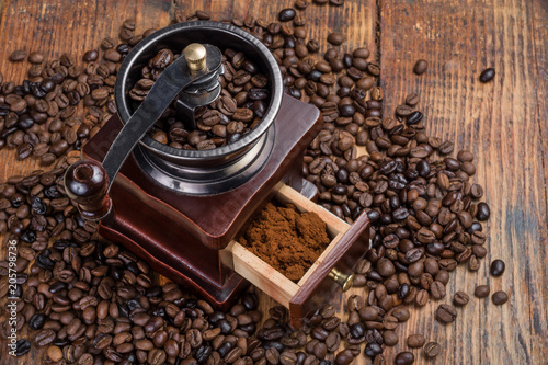 Coffee mill on rustic wooden plank background and roasted coffee beans. Food and drink concept