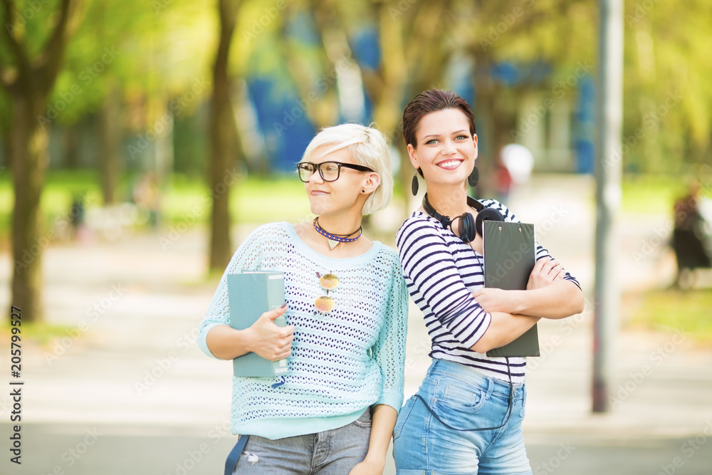 Two female students standing outdoors and posing Two female students standing outdoors and posing