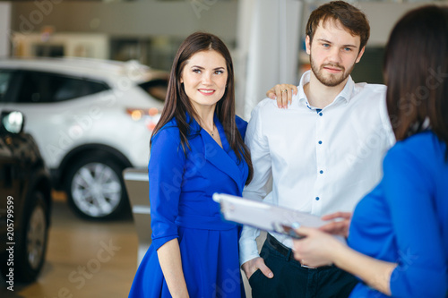 Beautiful cheerful couple buying a car in car dealership photo