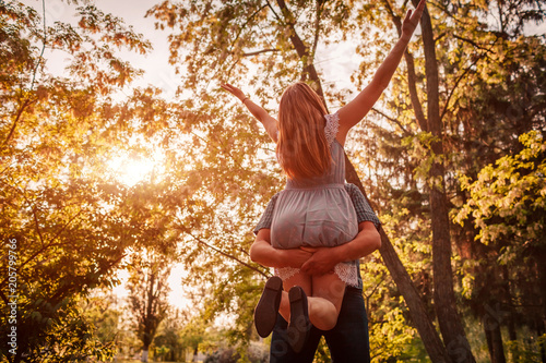 Happy couple having fun in blooming garden. Man holds his girlfriend in hands and spins at sunset. Guys enjoying life