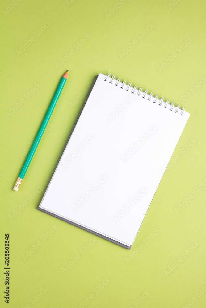 Blank notebook with pencil on green pastel background. Flat lay concept. Vertical orientation Blank notebook with pencil on green pastel background. Flat lay concept. Vertical orientation
