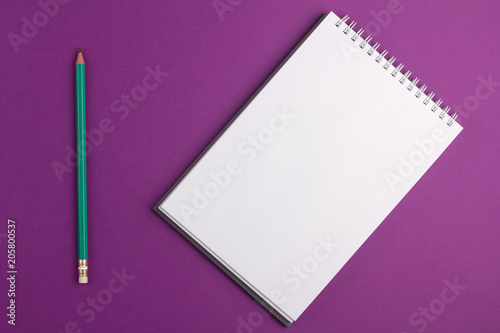 Blank notebook with pencil on purple background. Flat lay concept
