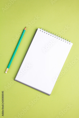 Blank notebook with pencil on green pastel background. Flat lay concept. Vertical orientation