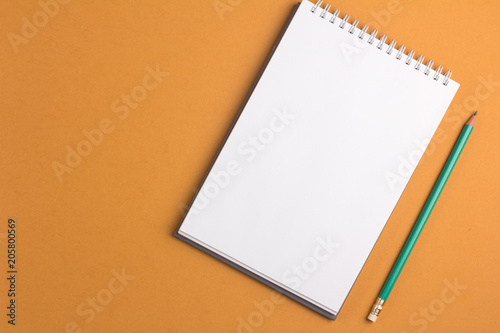 Blank notebook with pencil on orange pastel background. Flat lay concept. Copy space