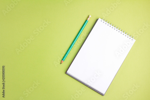 Blank notebook with pencil on green pastel background. Flat lay concept. Copy space