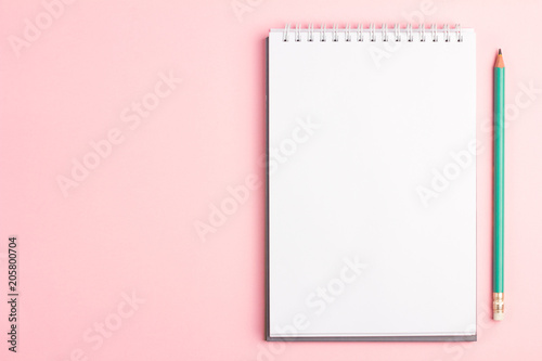 Blank notebook with pencil on pink pastel background. Flat lay concept with copy space